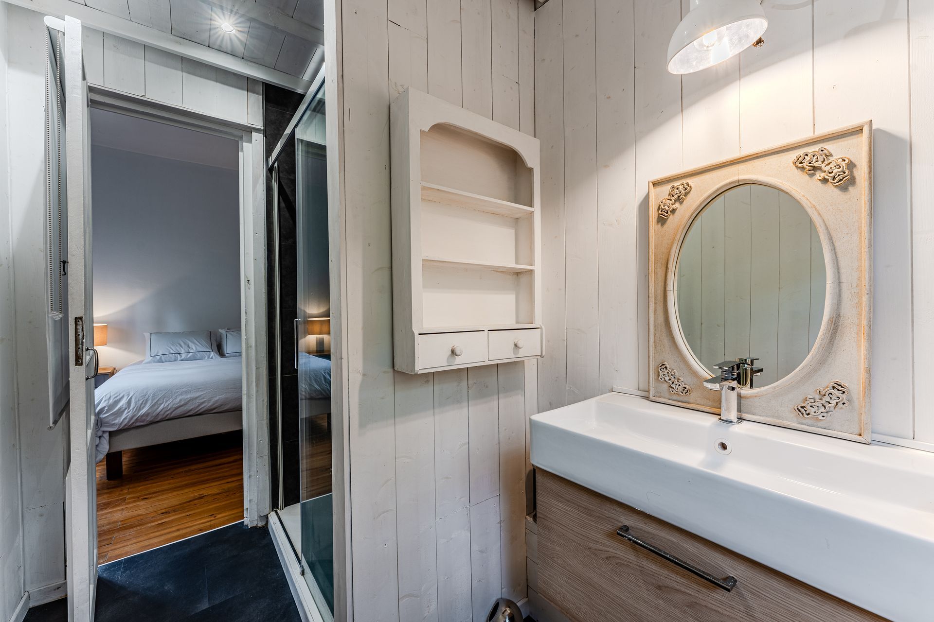 Une salle de bain avec un lavabo, un miroir et une étagère.