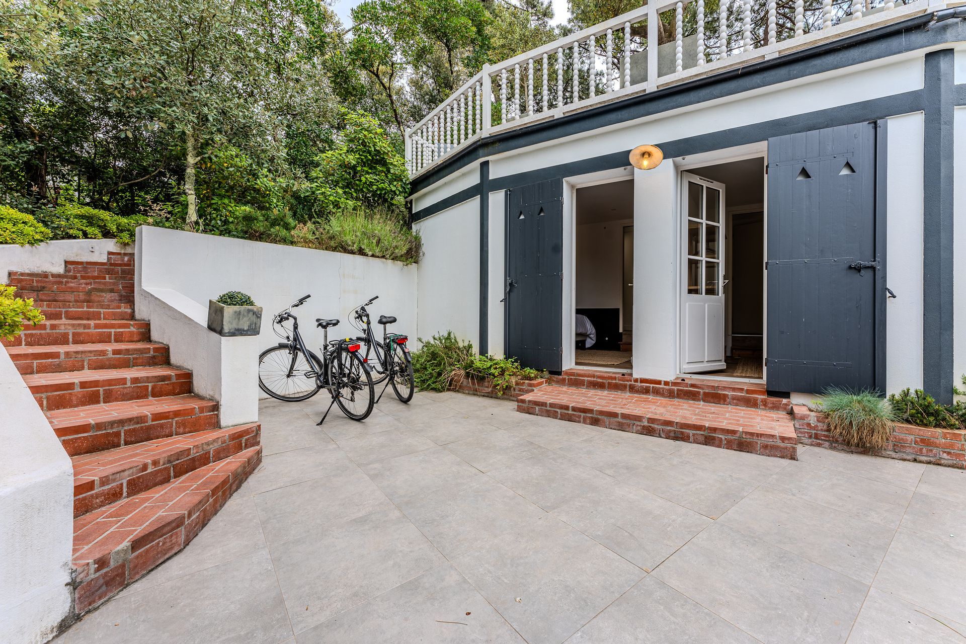 Deux vélos sont garés devant une maison avec des escaliers qui y mènent.