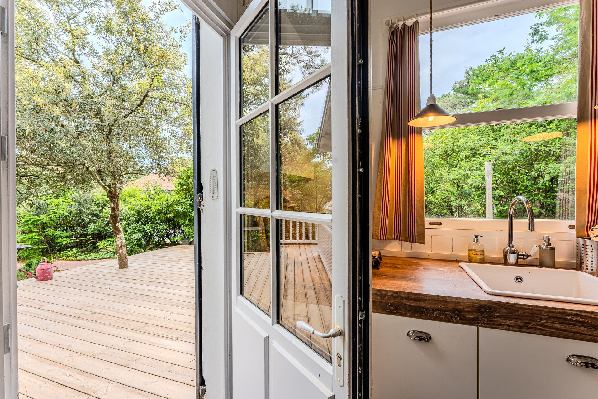 Une cuisine avec un évier et une fenêtre avec vue sur une terrasse.