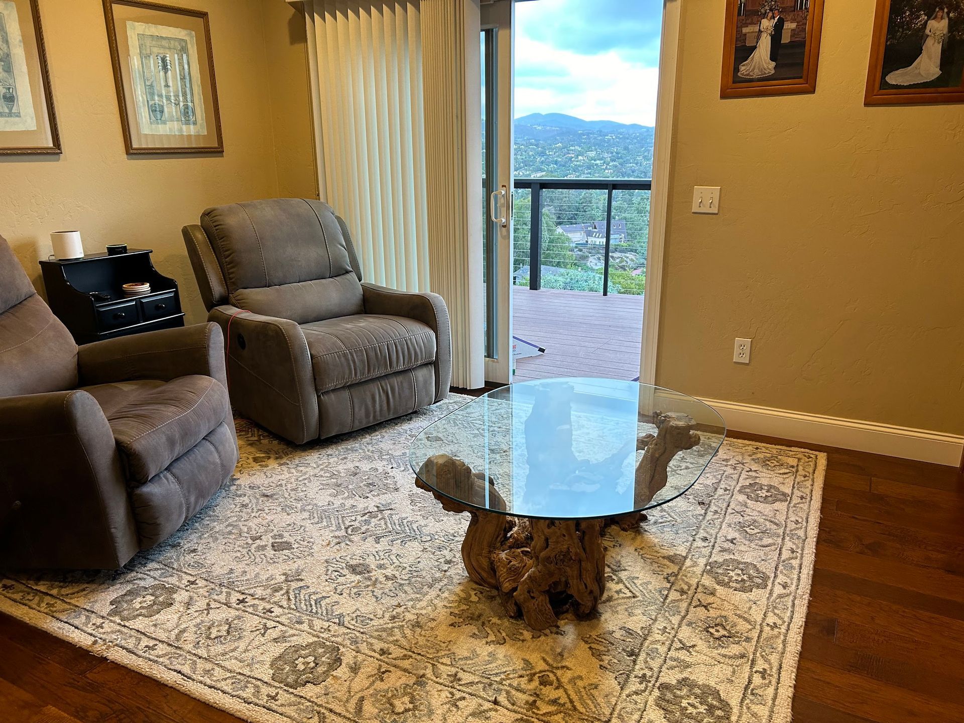 Two recliners in a living room with a glass-top coffee table, rug, and a balcony overlooking a mountain view.