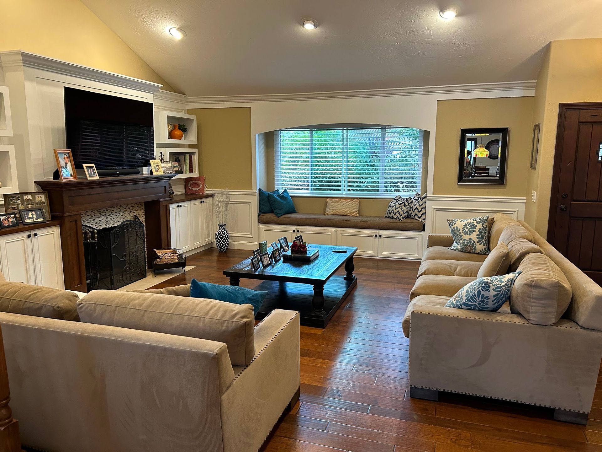 Living room with fireplace, window seat, sofas, and dark wood floors.