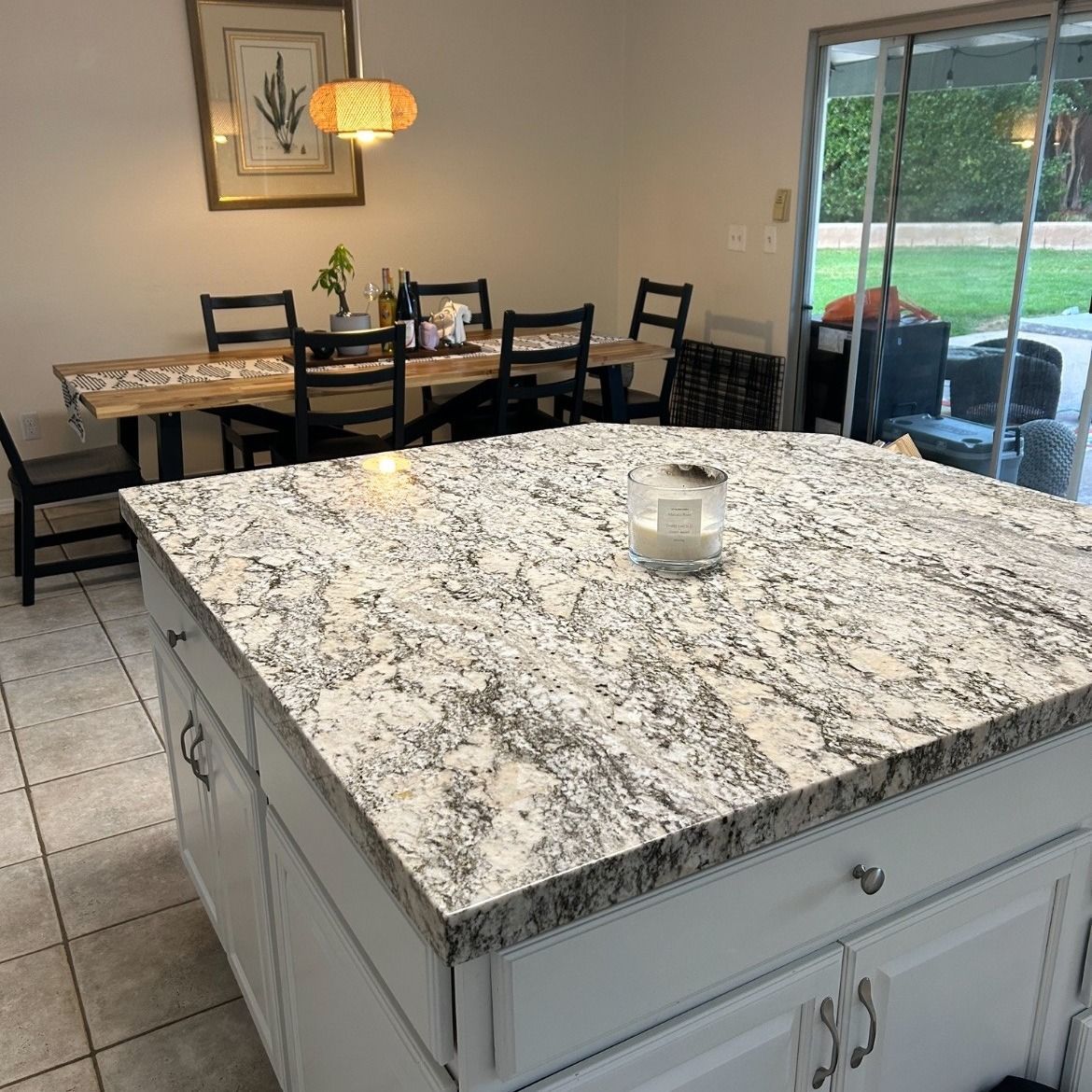 Kitchen island with a granite countertop and a dining area in the background.
