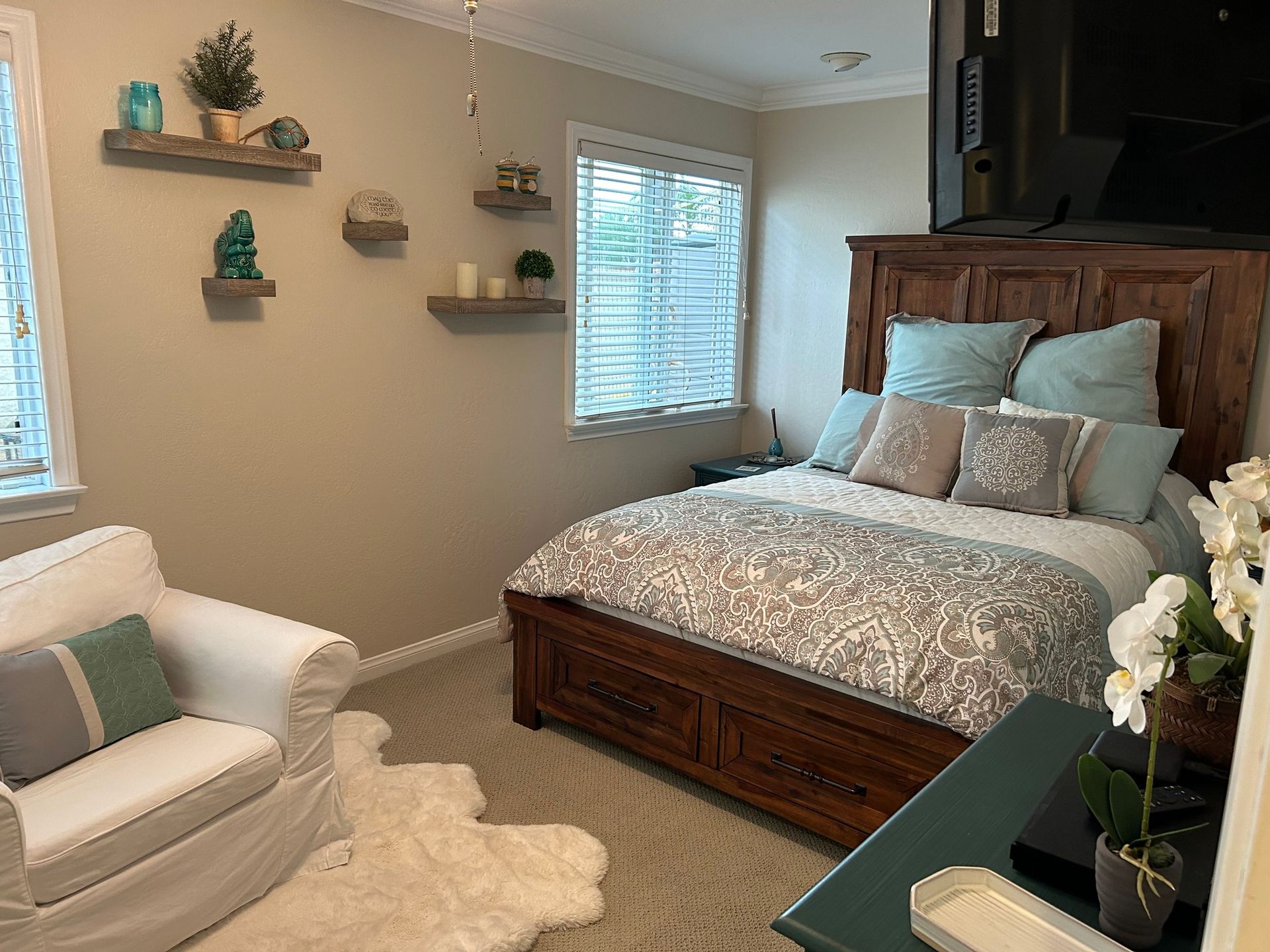 Bedroom with a bed, armchair, shelves, and window; neutral colors, cozy atmosphere.