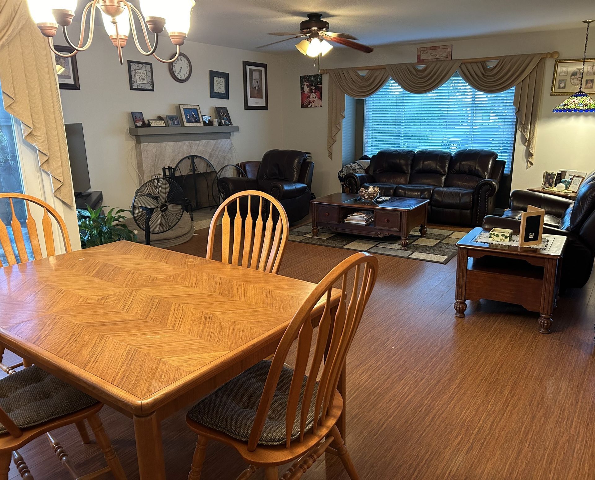 Dining room with wooden table, chairs, and view of living room with furniture and a window.