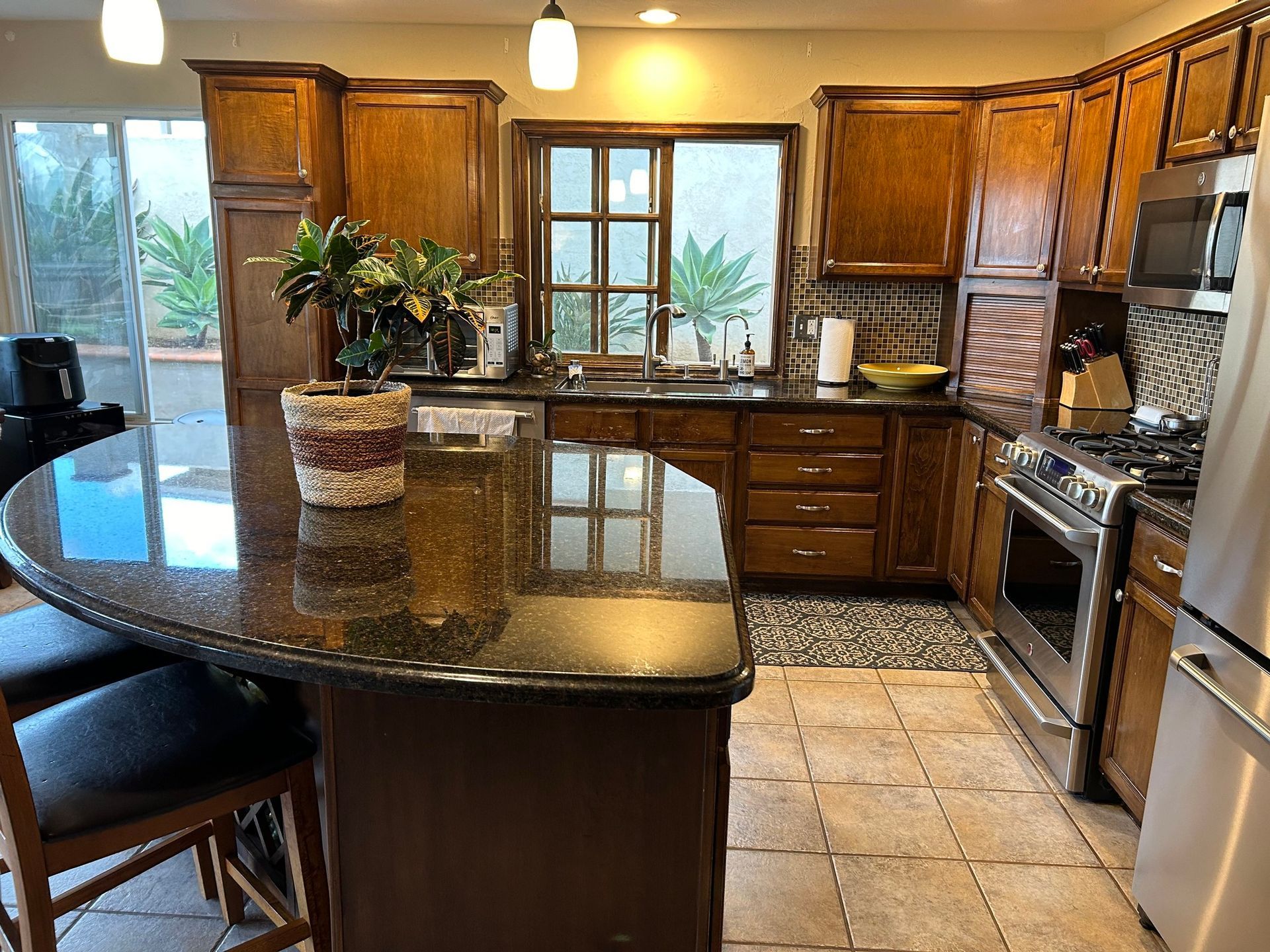 Kitchen with dark wood cabinets, granite island, stainless steel appliances, and view to patio.