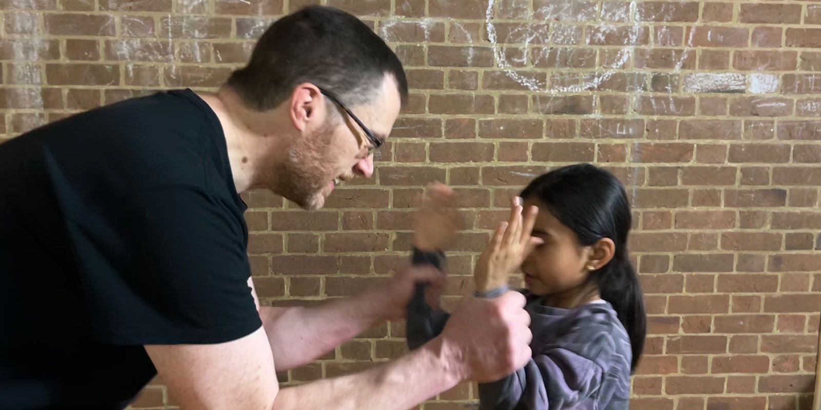 A threatening man holding a child by her wrists