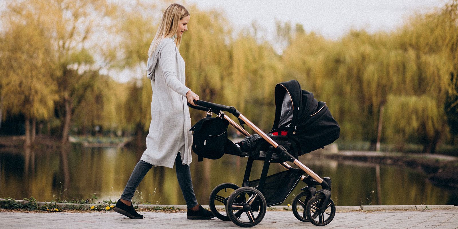 Young mother pushing a pram in a park