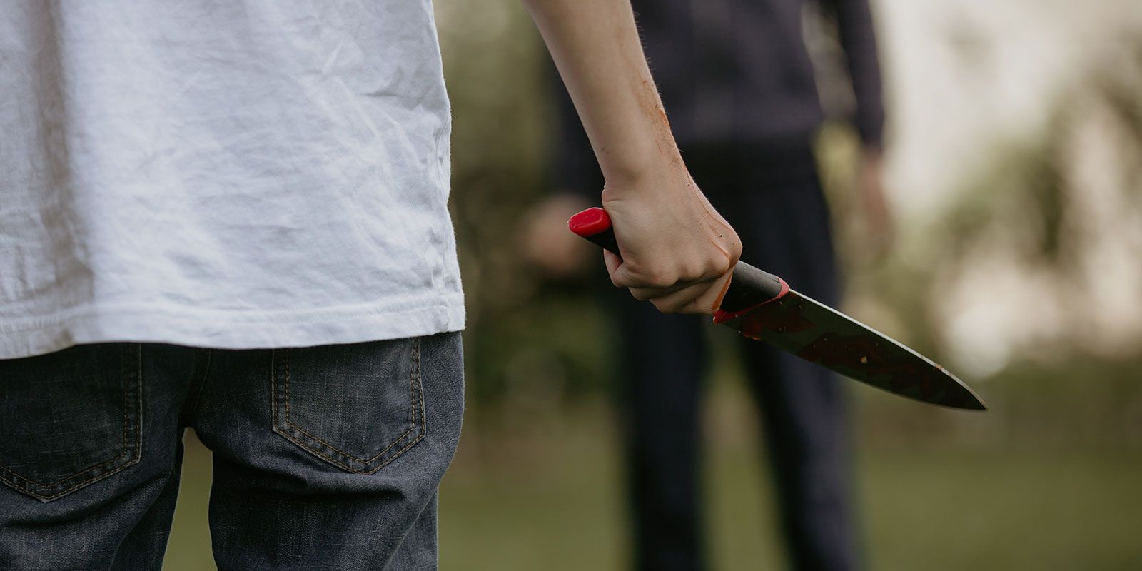Two teenagers facing off, one holds a knife