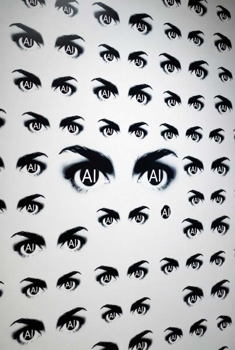 Wet city street with cars and buildings reflecting lights under a cloudy sky.