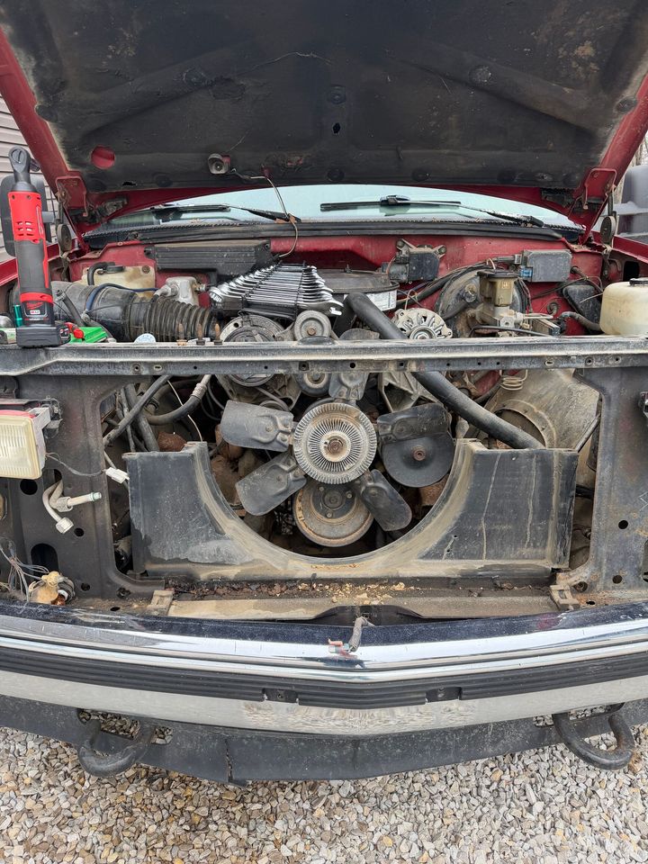 Red truck with the hood open, revealing the engine bay, cooling fan, and front grill area.