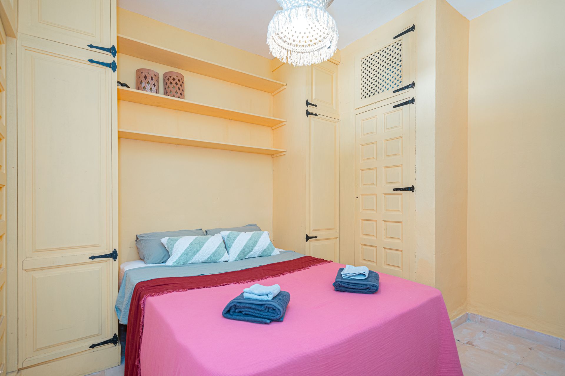 Een slaapkamer met een bed en een kroonluchter die aan het plafond hangt van Villa Fave in Javea 