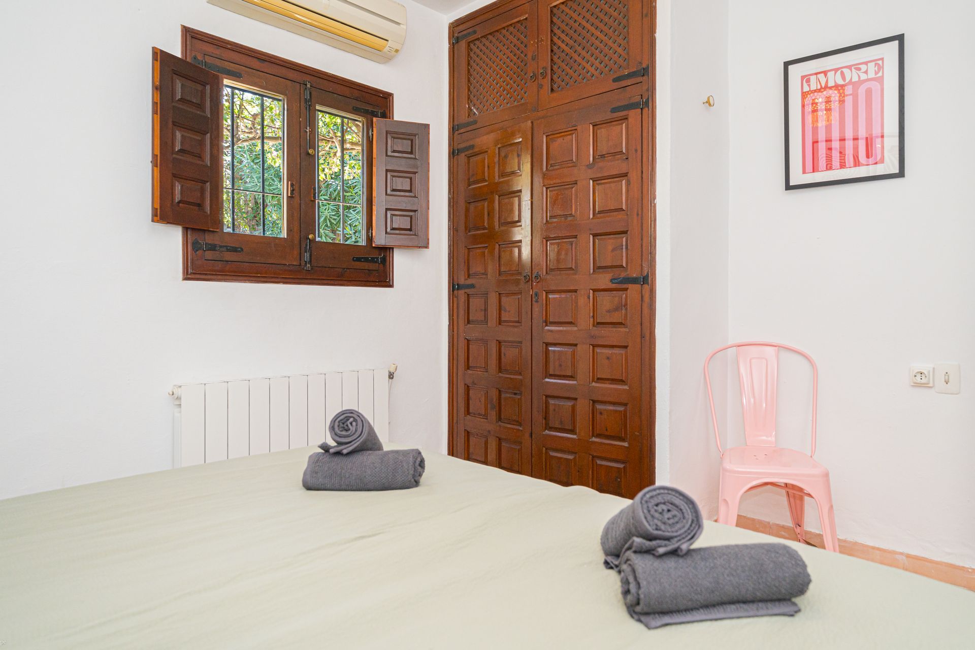 Ein Schlafzimmer mit einem rosa Stuhl und einem Bild an der Wand, auf dem Rio steht