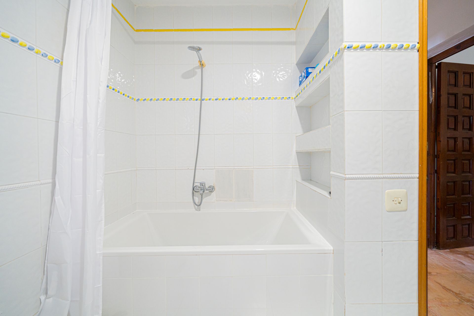 Ein Badezimmer mit weißen Fliesen sowie Badewanne und Dusche