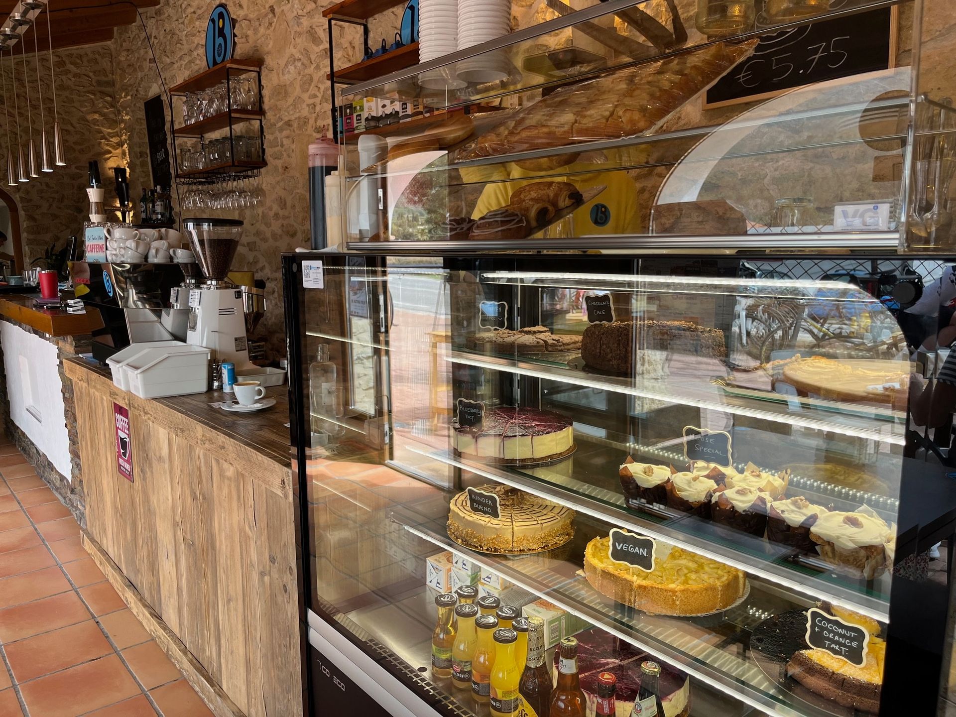Een bakkerij met een glazen vitrine vol met desserts