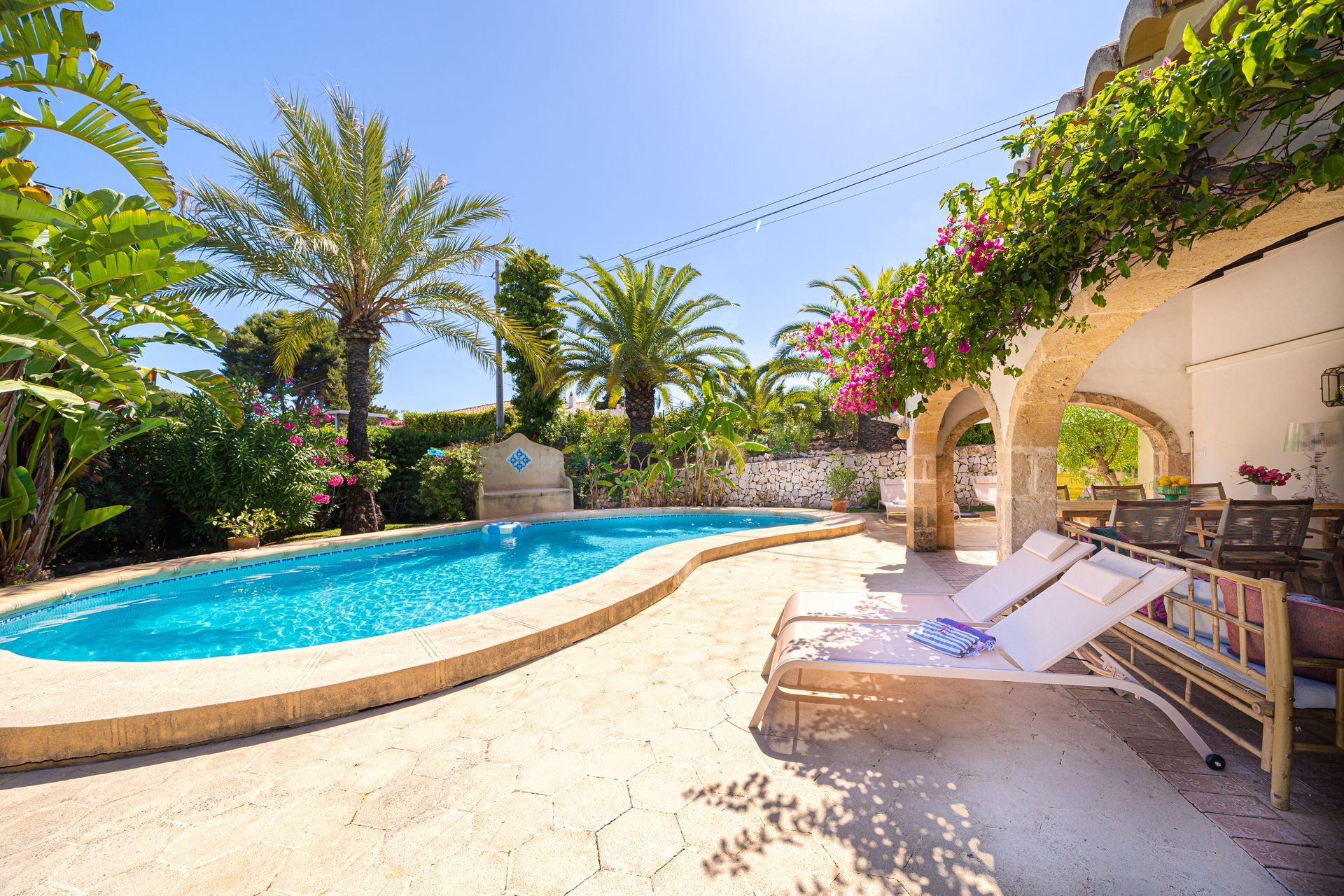 Una piscina rodeada de palmeras y tumbonas.