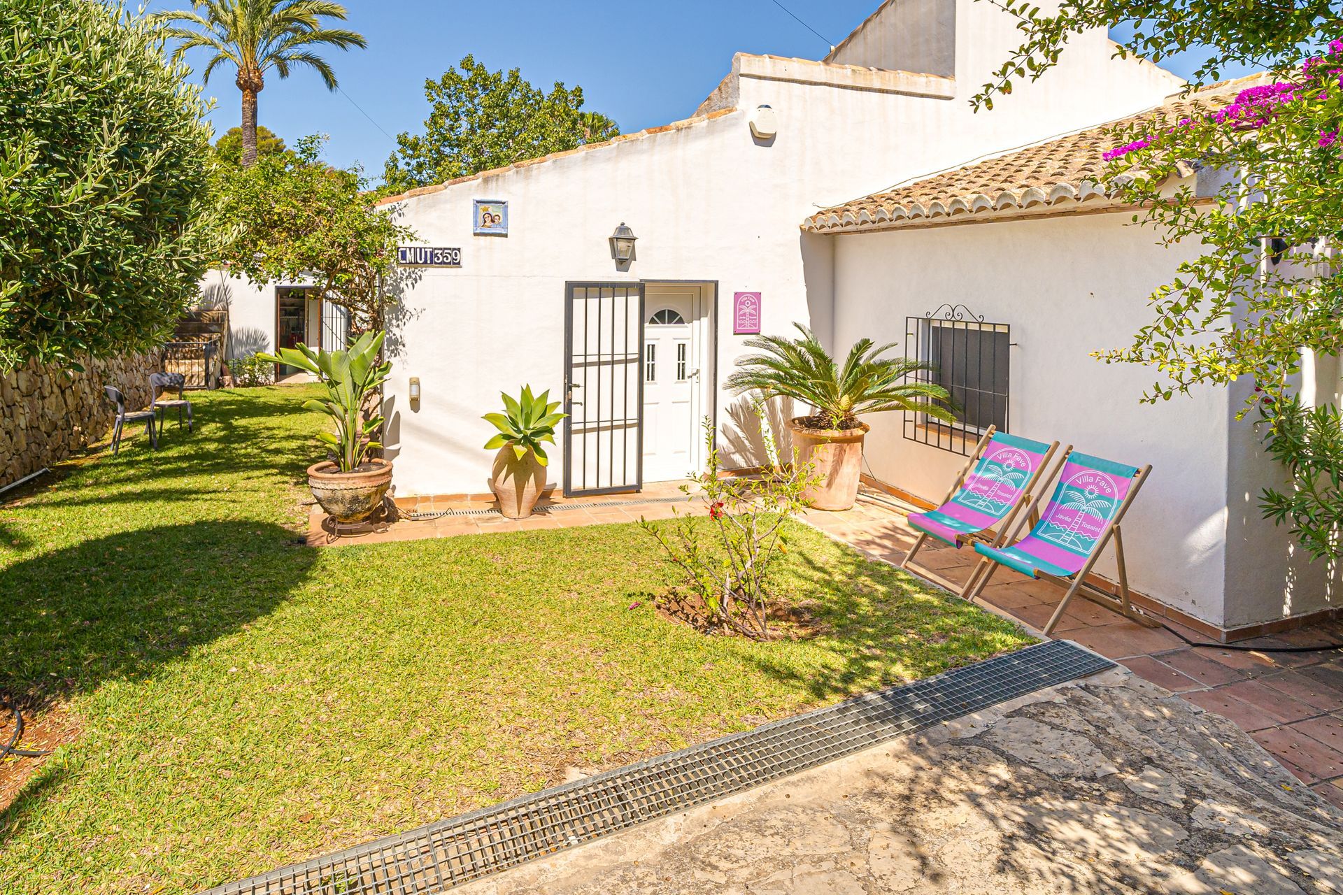 Un edificio blanco con una puerta negra y un muro de piedra.