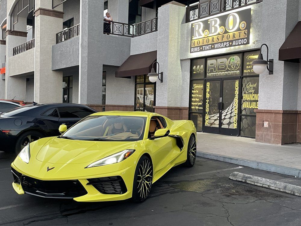 Bright yellow sports car parked outside a restaurant storefront