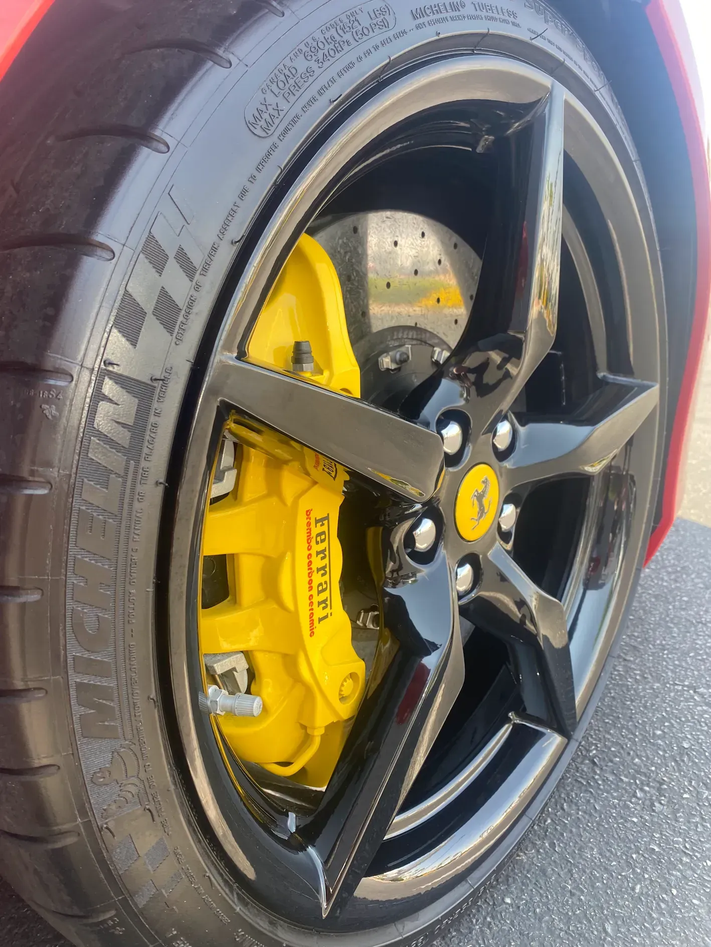 Close-up of a black wheel with yellow brake caliper on a red car.