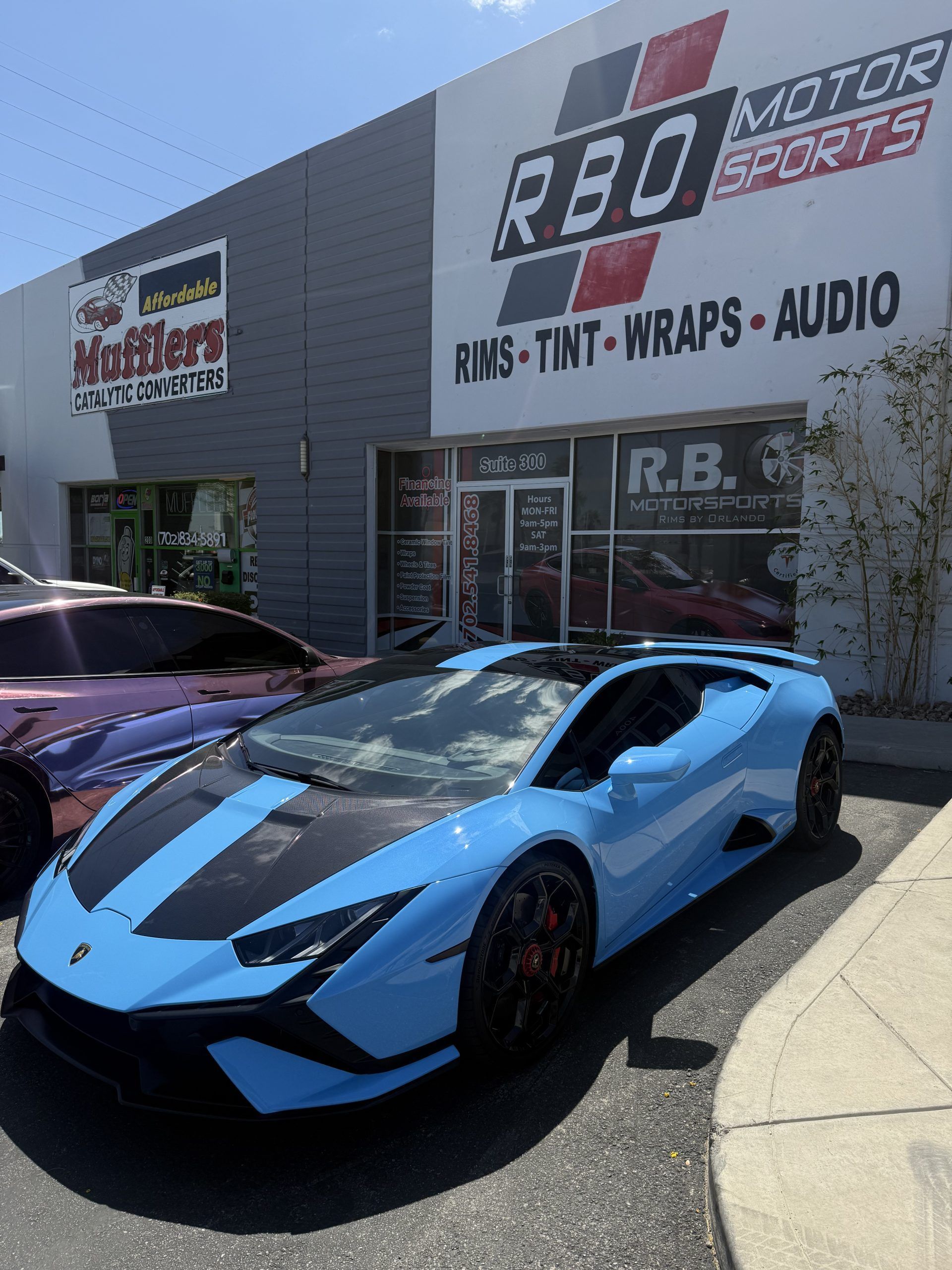 Blue Lamborghini parked outside R&D Motor Sports shop with performance signage