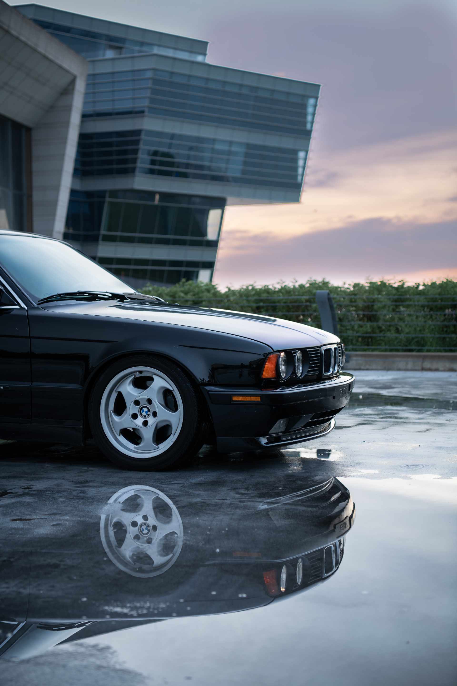 black BMW parked in a lot with puddles reflecting the car