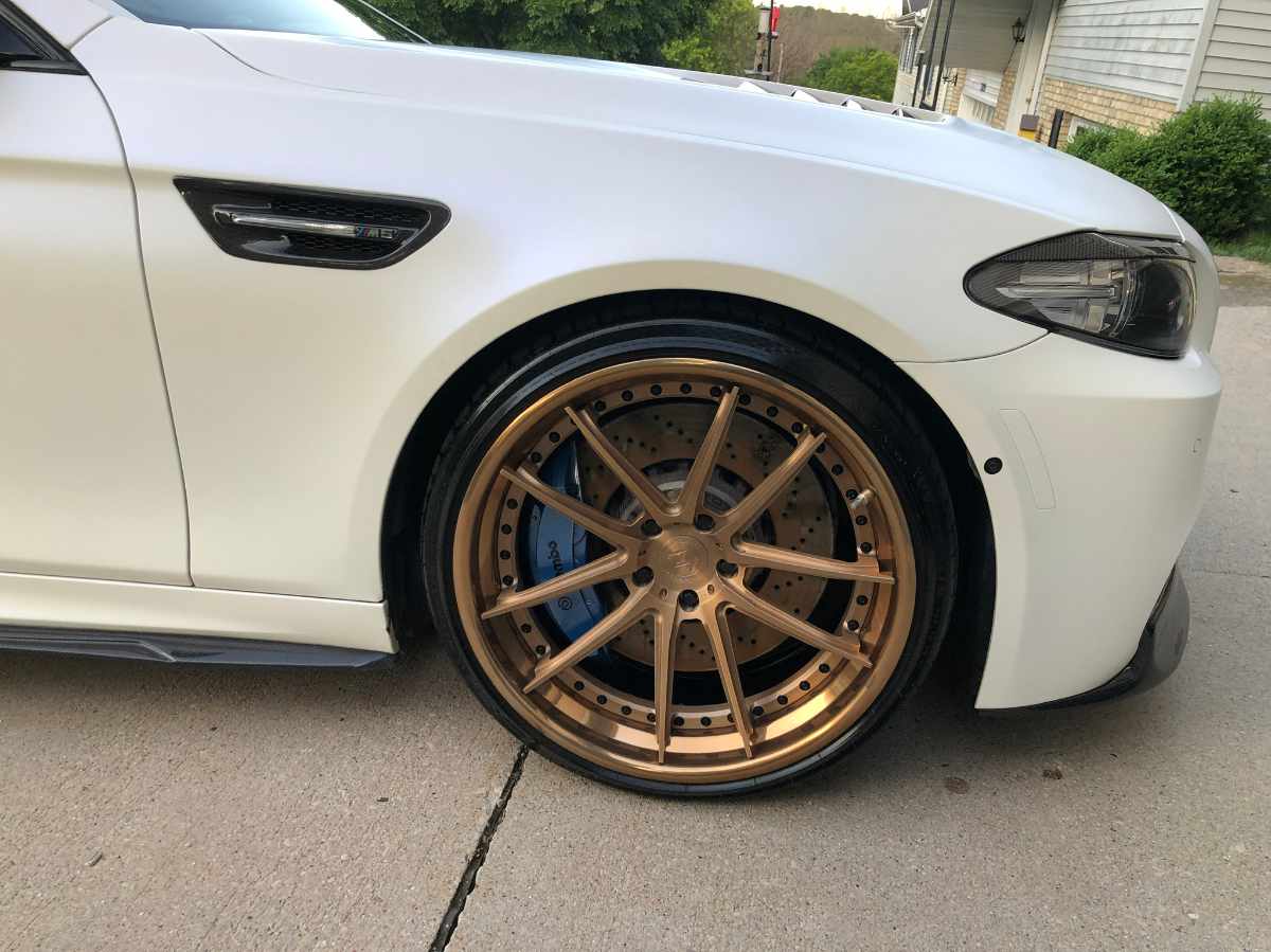 clean white BMW front quarter with bronze wheels in a driveway