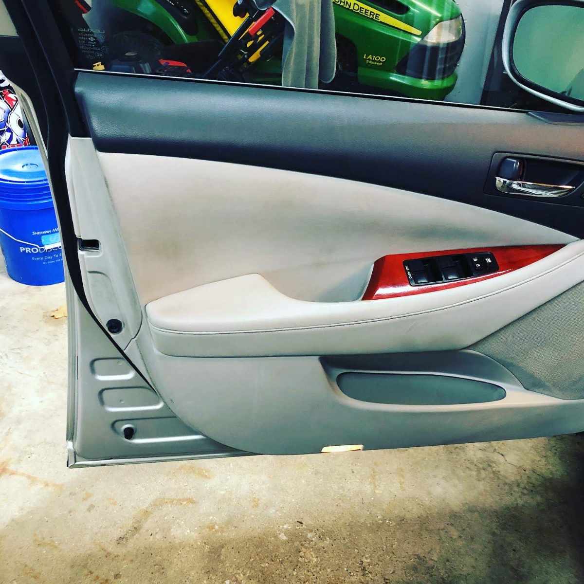 Beige and gray car door interior with wood accents, window controls.
