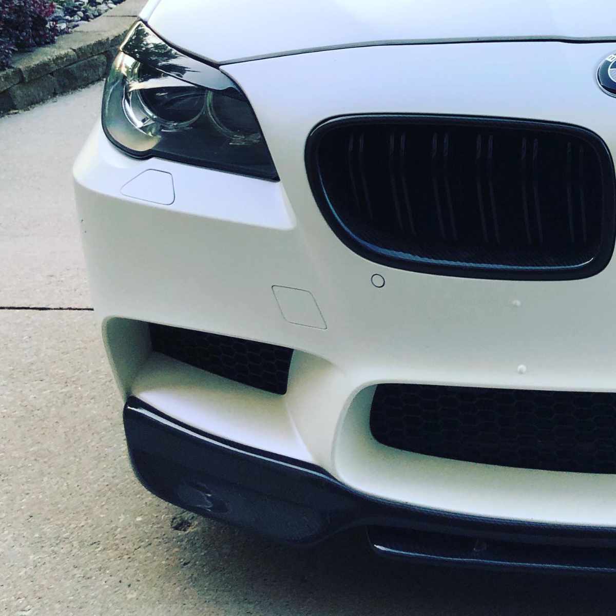 clean white BMW front bumper in a driveway