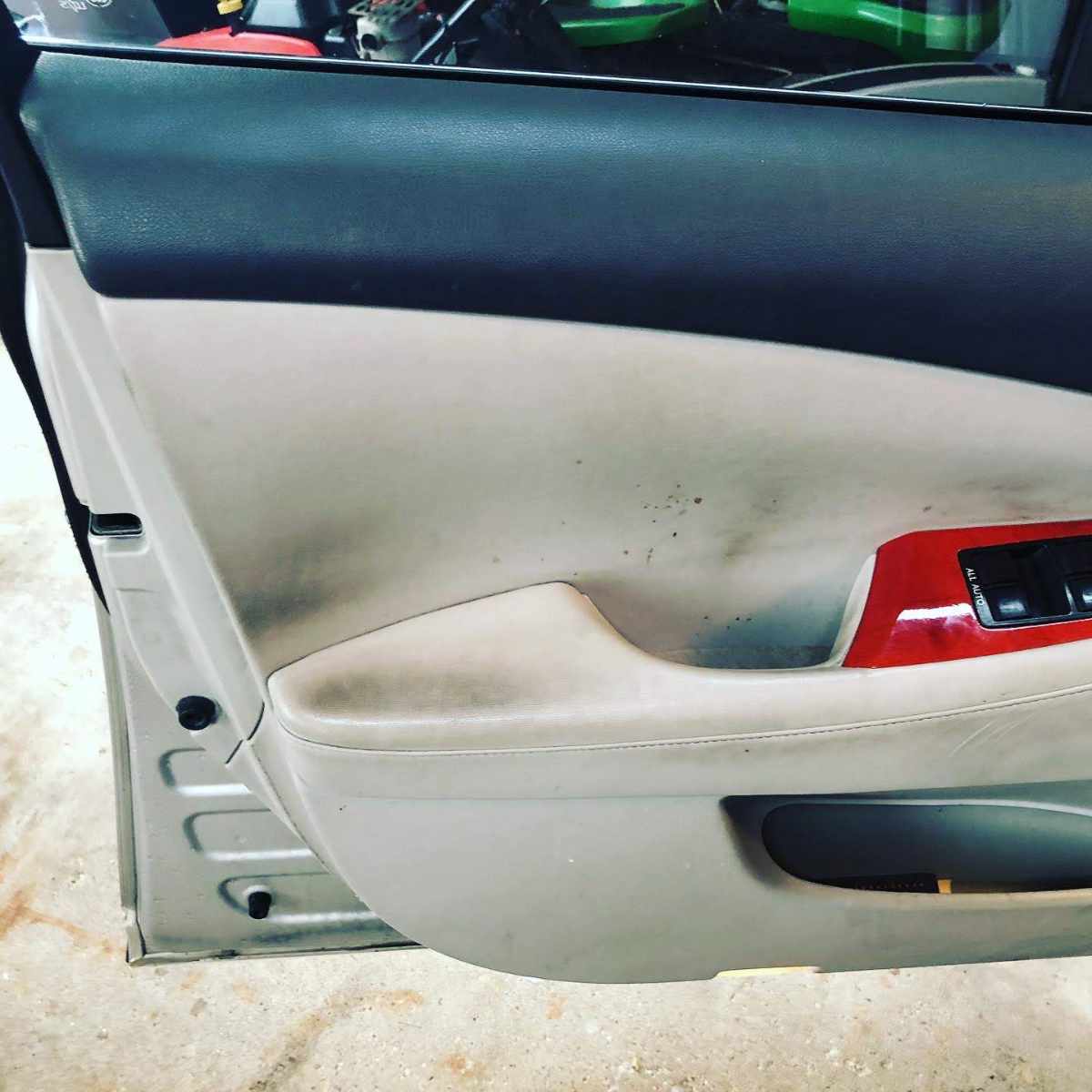 Beige car door interior with dark stains, red trim, and black buttons.
