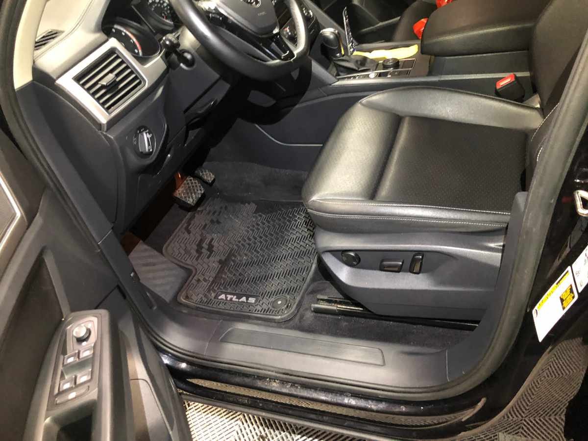 Interior of a black car with leather seats and a floor mat labeled