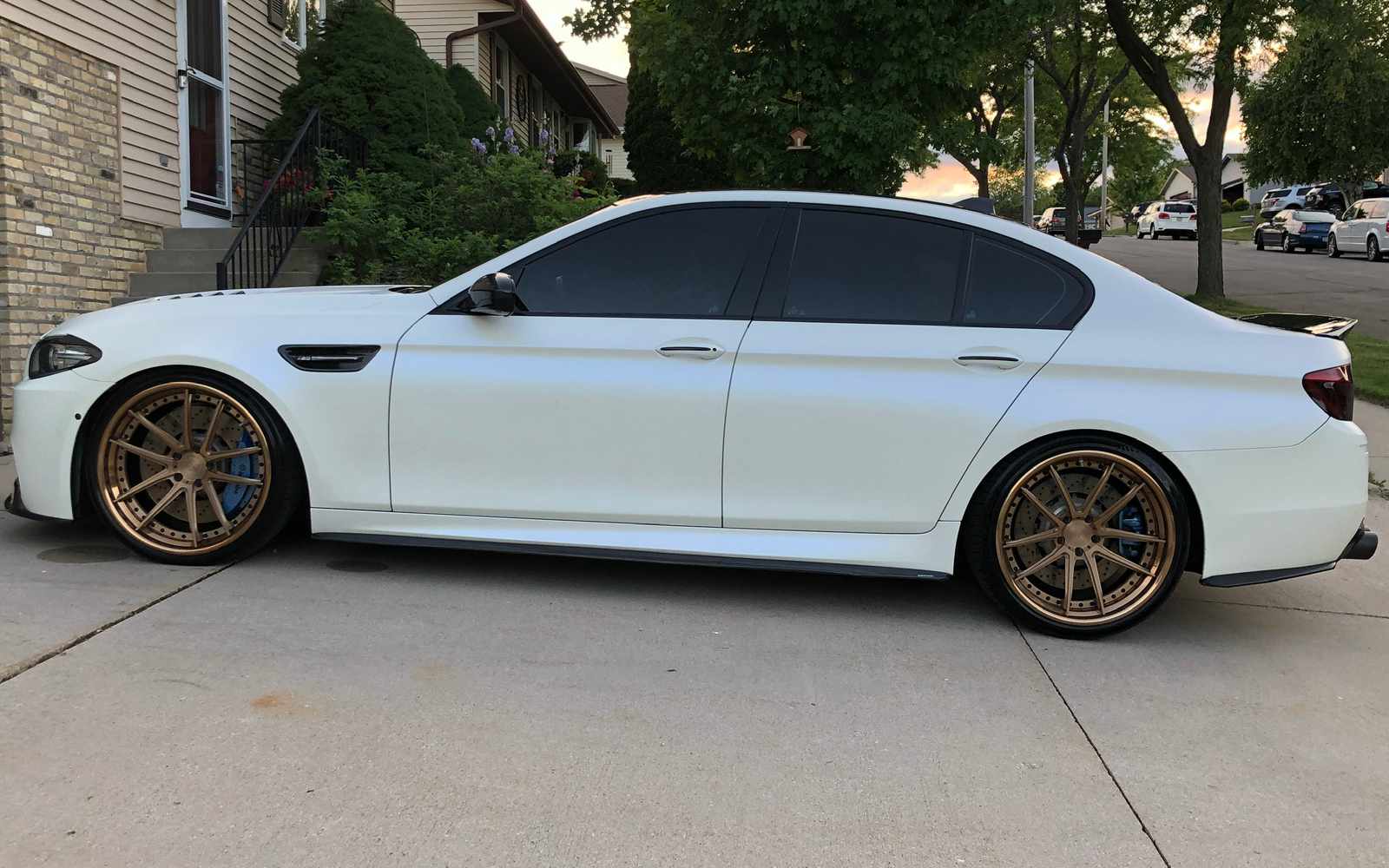clean white BMW with bronze wheels in a driveway