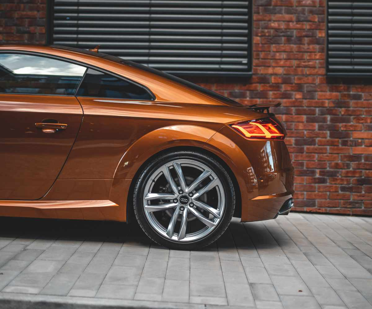 polished bronze Audi parked in front of a brick building