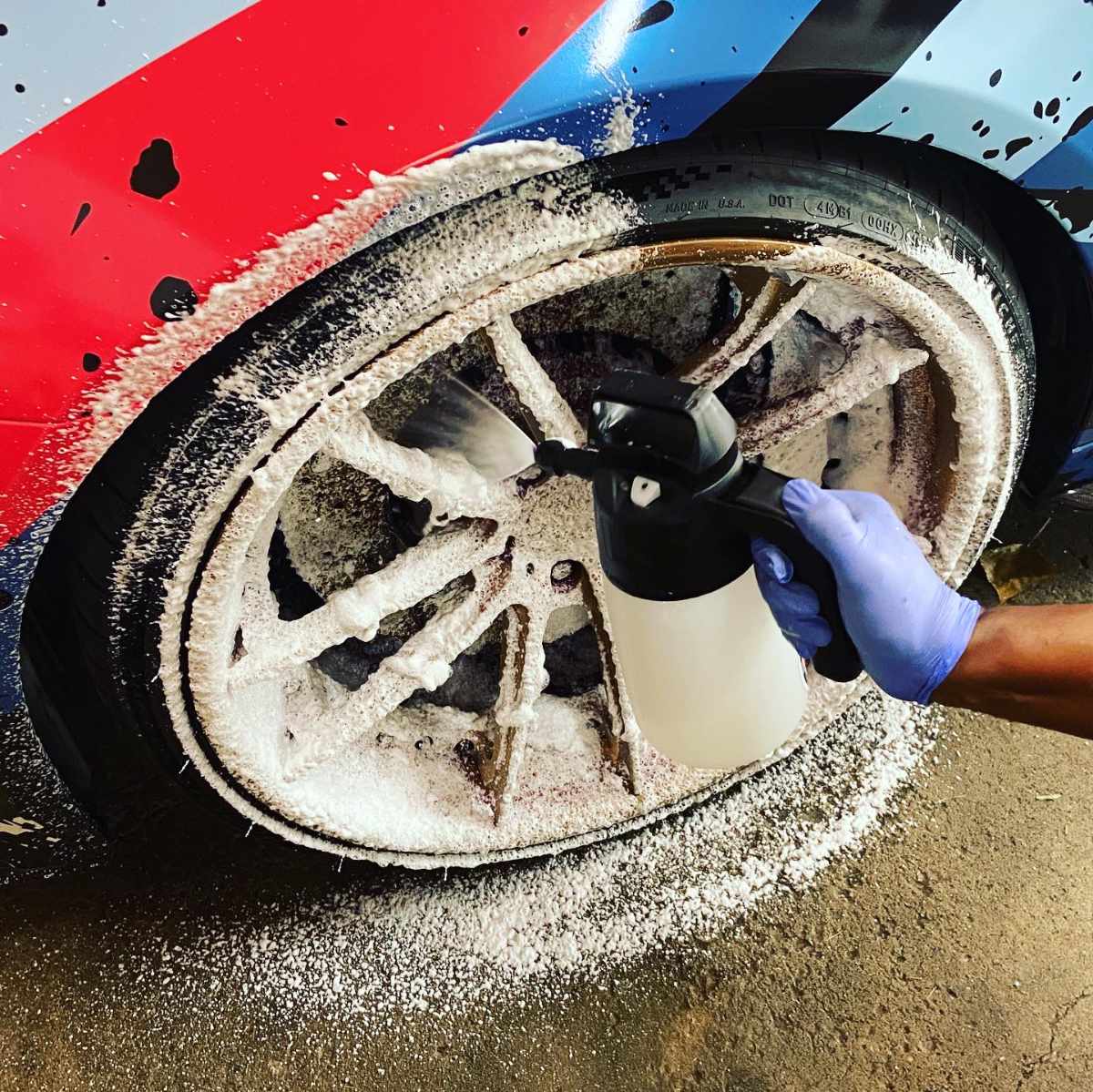 spraying foam on the wheel of custom wrapped BMW