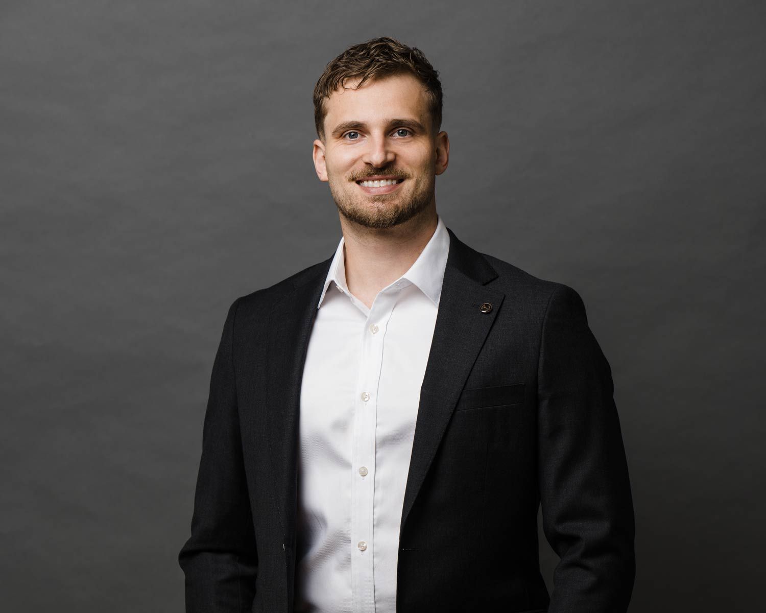 Man in a black suit and white shirt, smiling