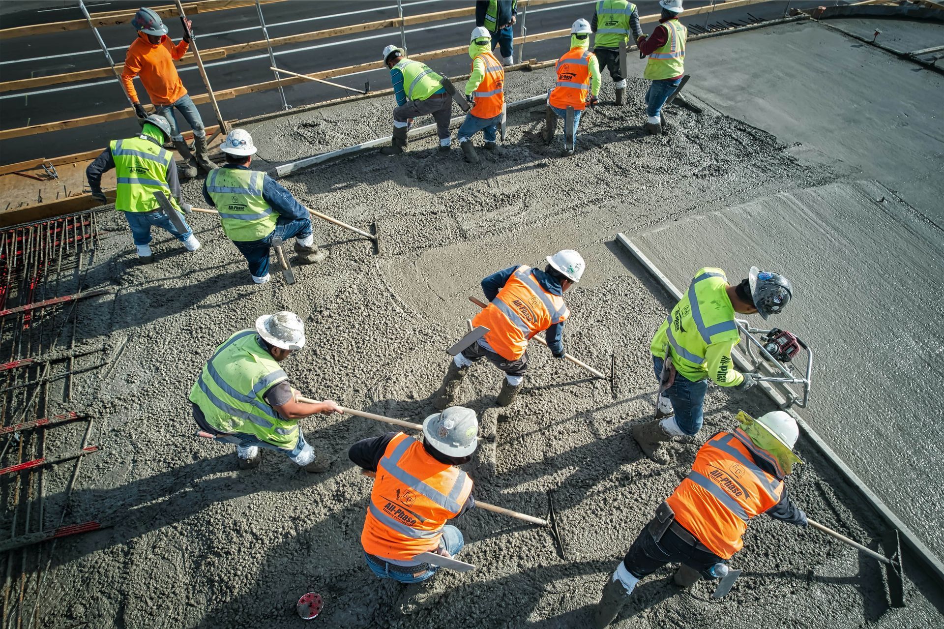 Construction workers in safety vests and hard hats leveling concrete