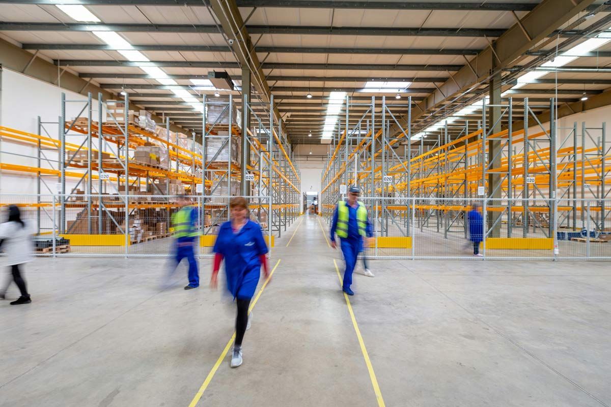 Warehouse interior with workers walking near yellow storage racks