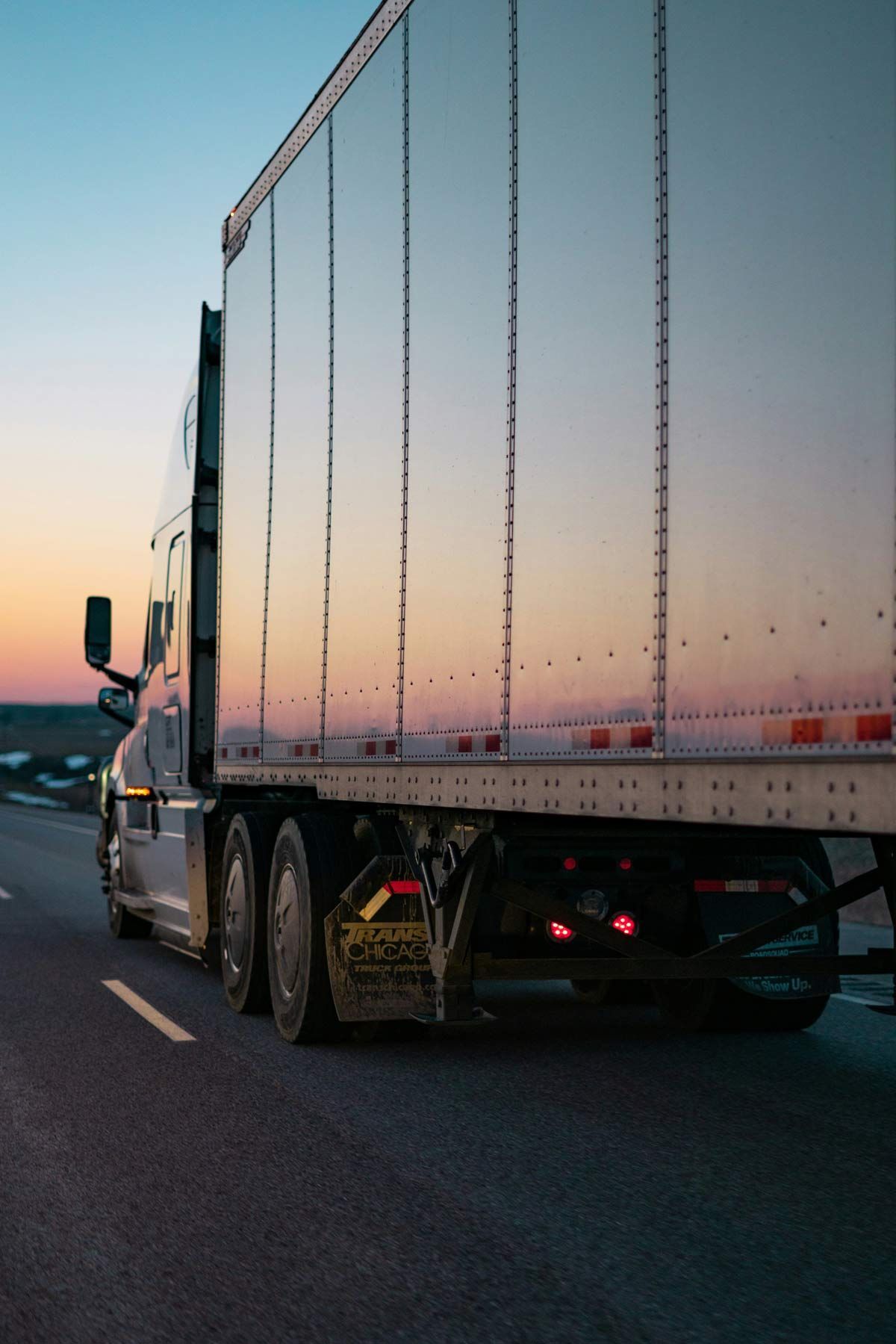 Semi-truck driving on a road at dusk