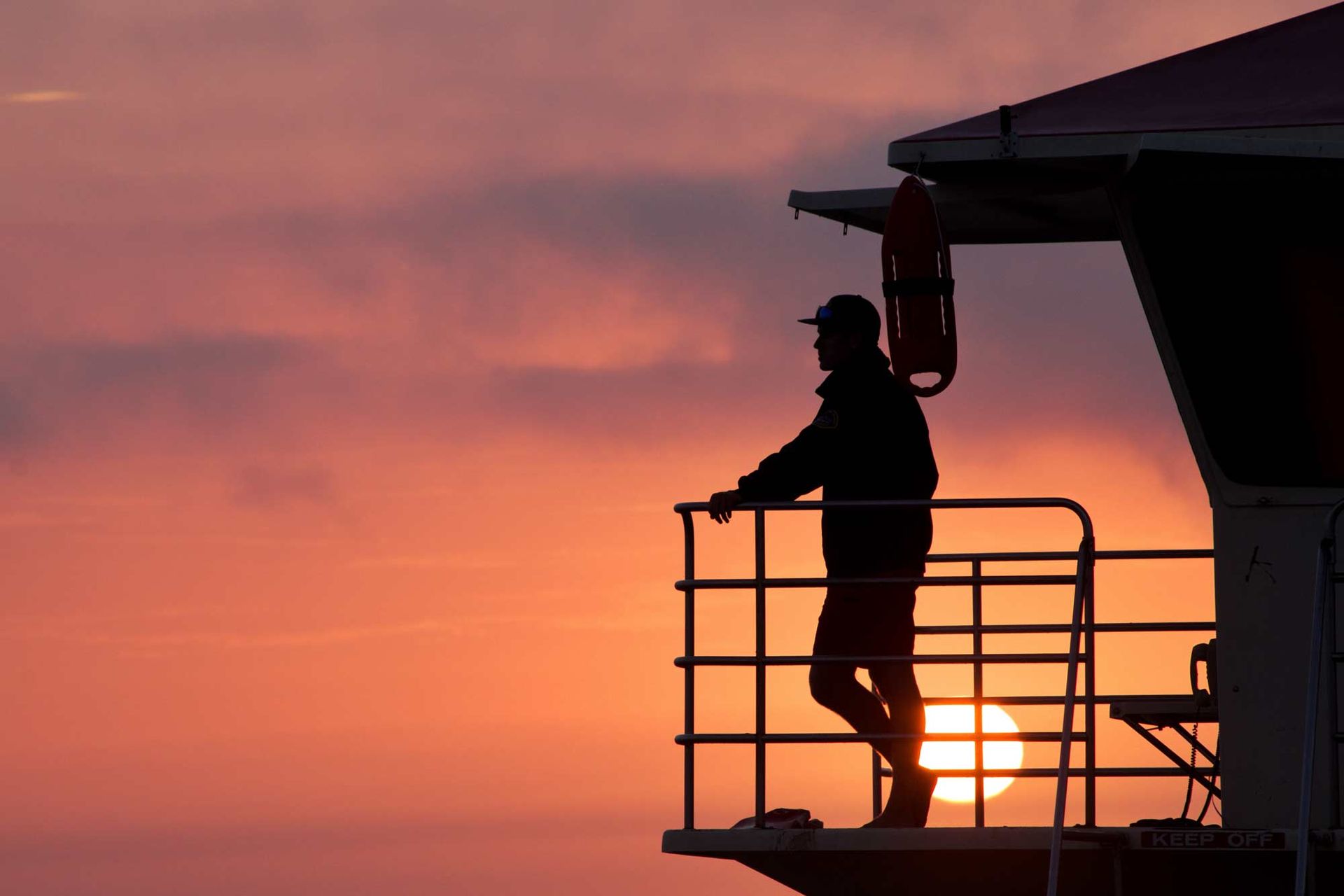 Silhouette of a person standing on a lifeguard tower