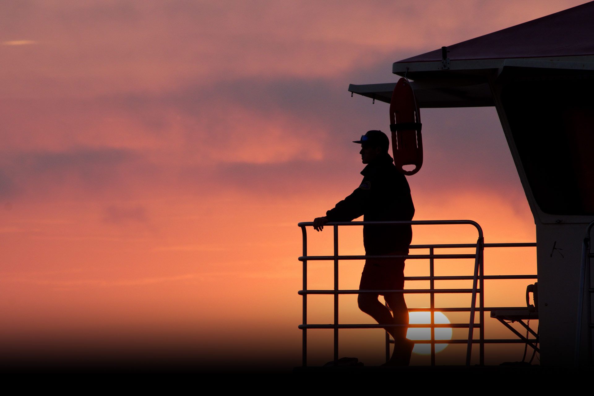 Silhouette of a person standing on a lifeguard tower
