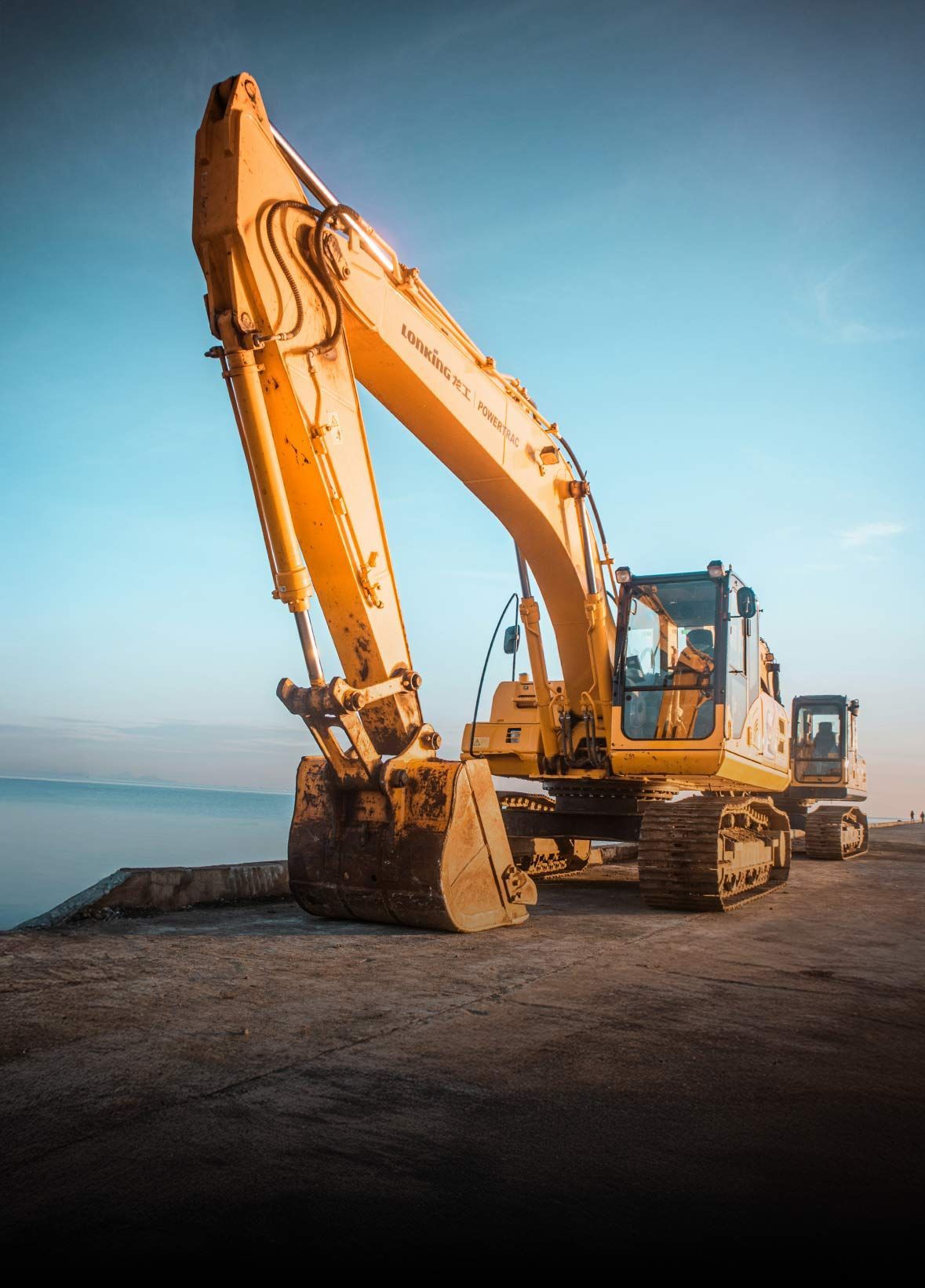 Yellow excavator on a concrete surface, boom raised