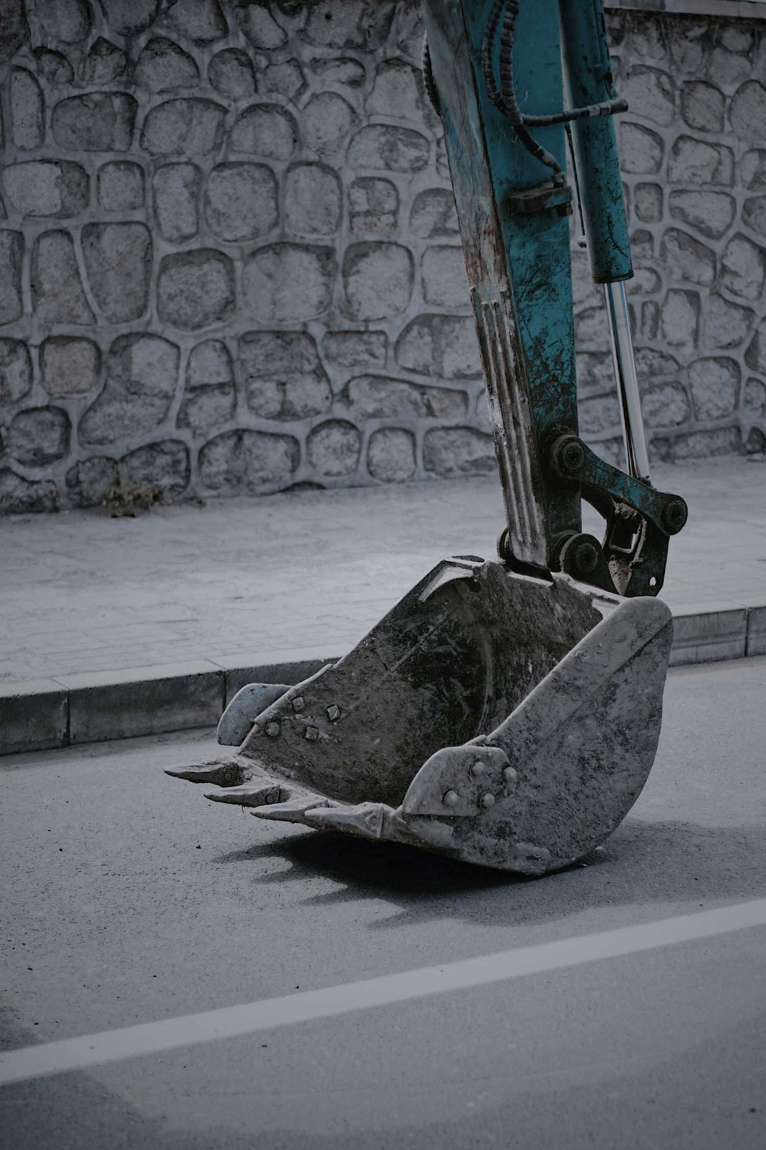 Blue and gray excavator bucket on asphalt road