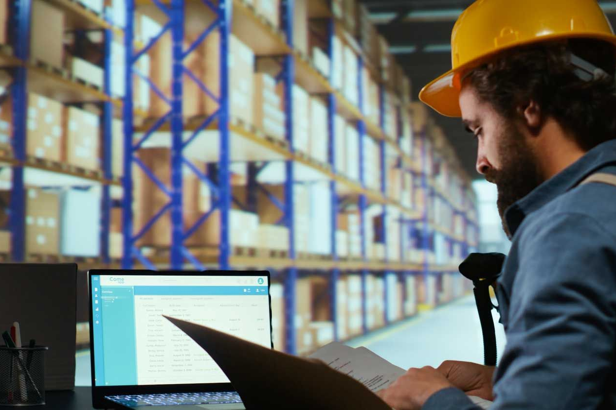 Man in hard hat reviewing papers in a warehouse