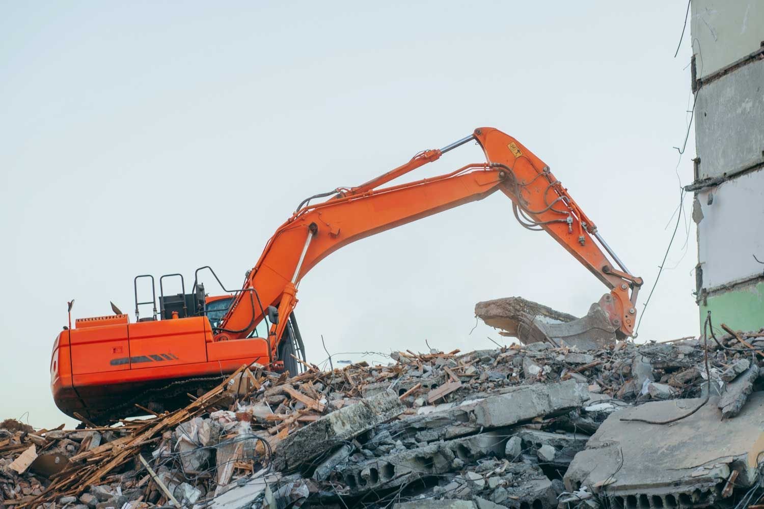 Orange excavator demolishing a building