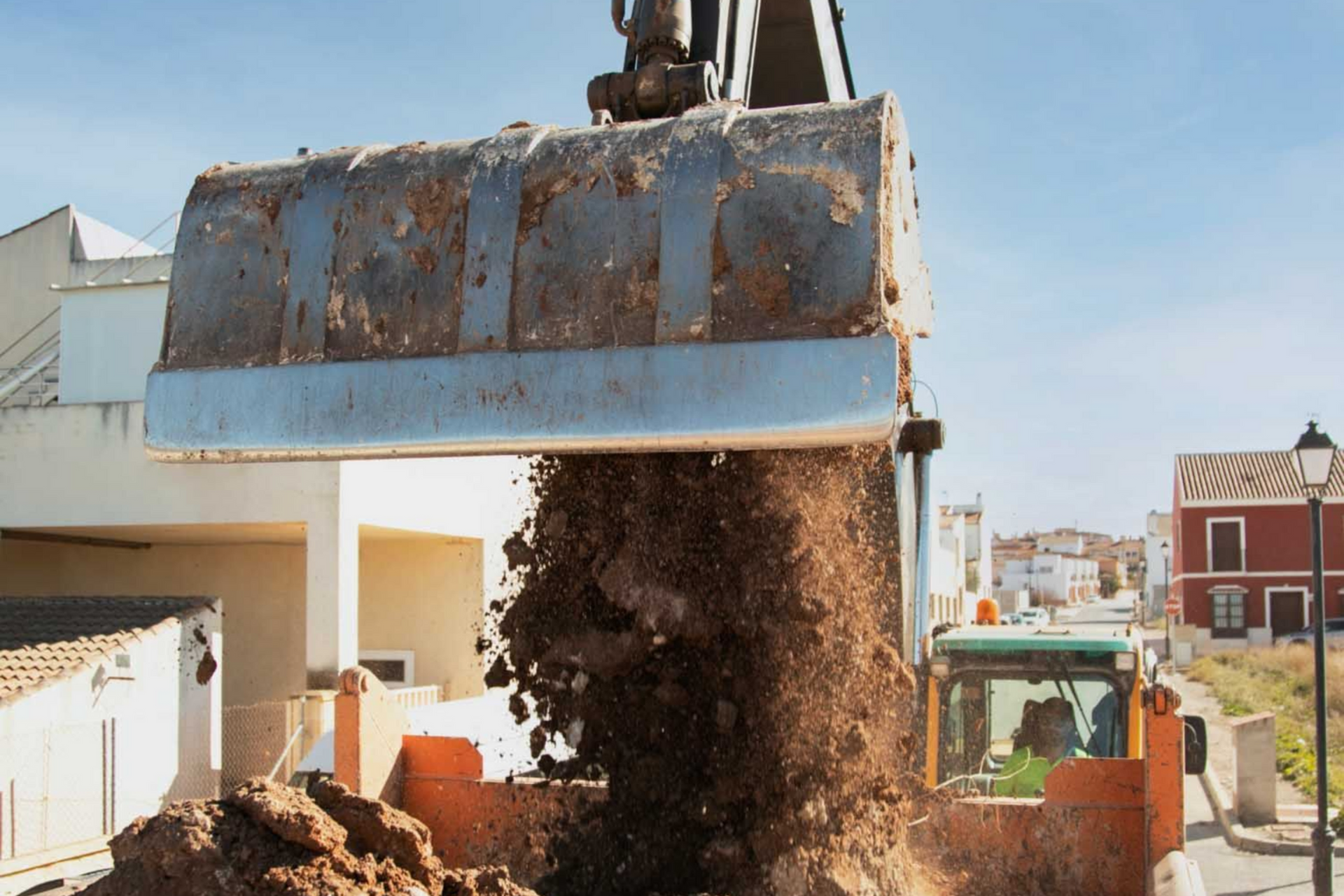 Excavator bucket dumping dirt into a truck
