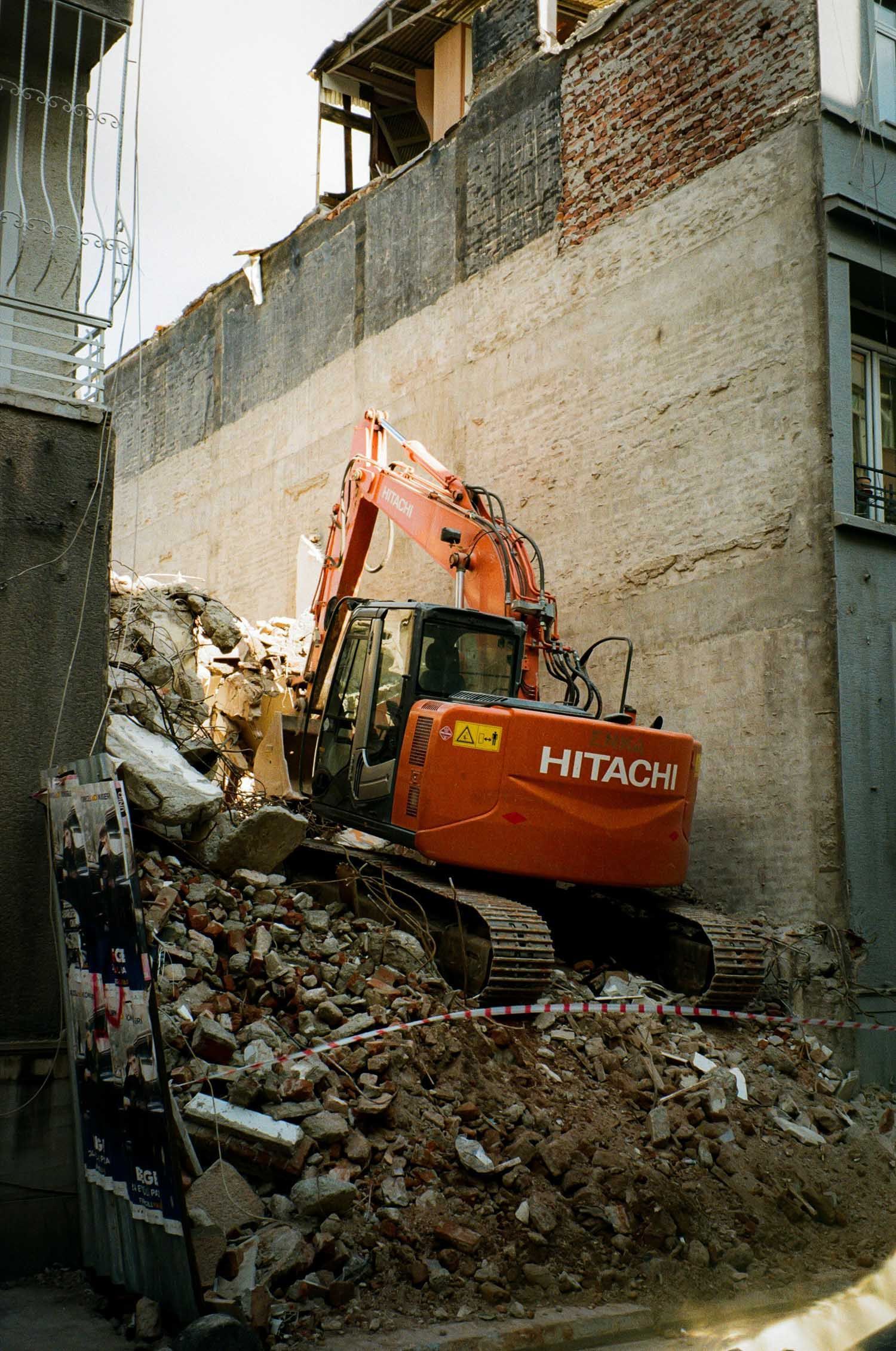 An orange Hitachi excavator demolishing a building