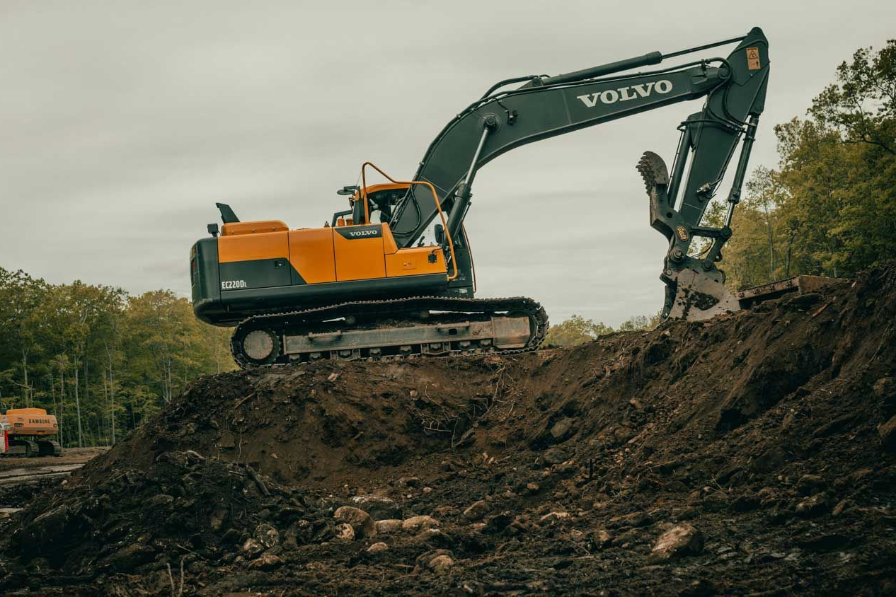 Yellow and black Volvo excavator on a dirt pile, digging