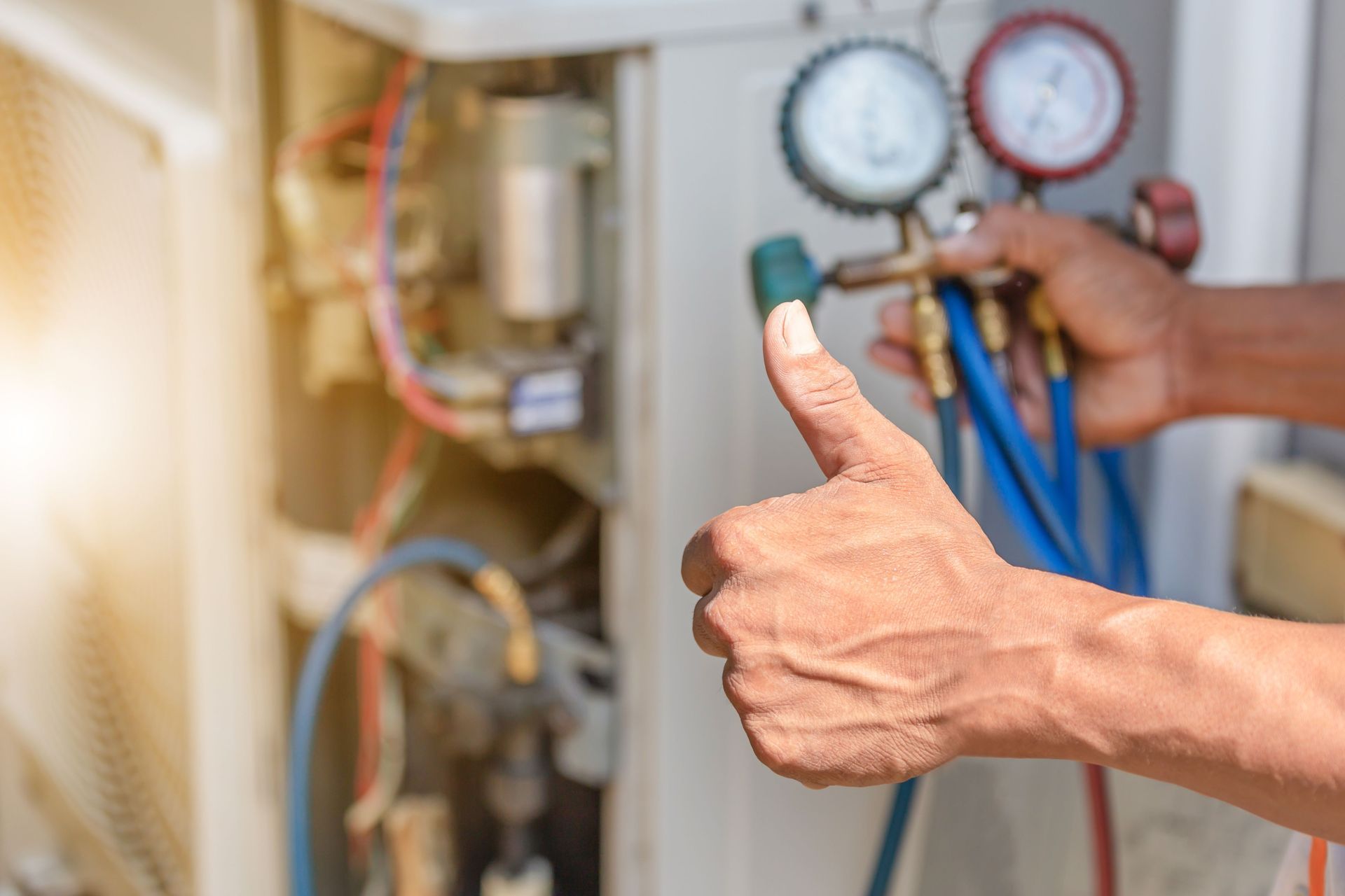 A man is giving a thumbs up while working on an air conditioner.