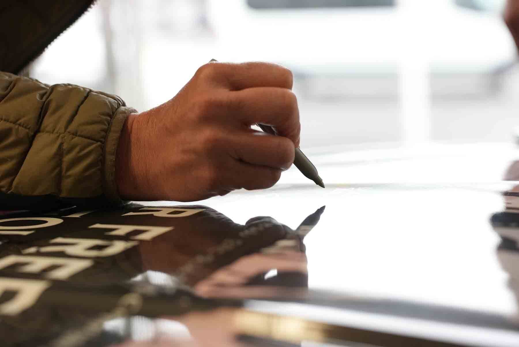 Man signing the hood of a car. | HALO FOR FREEDOM Warrior Foundation  Photo by: Charles Slaughter