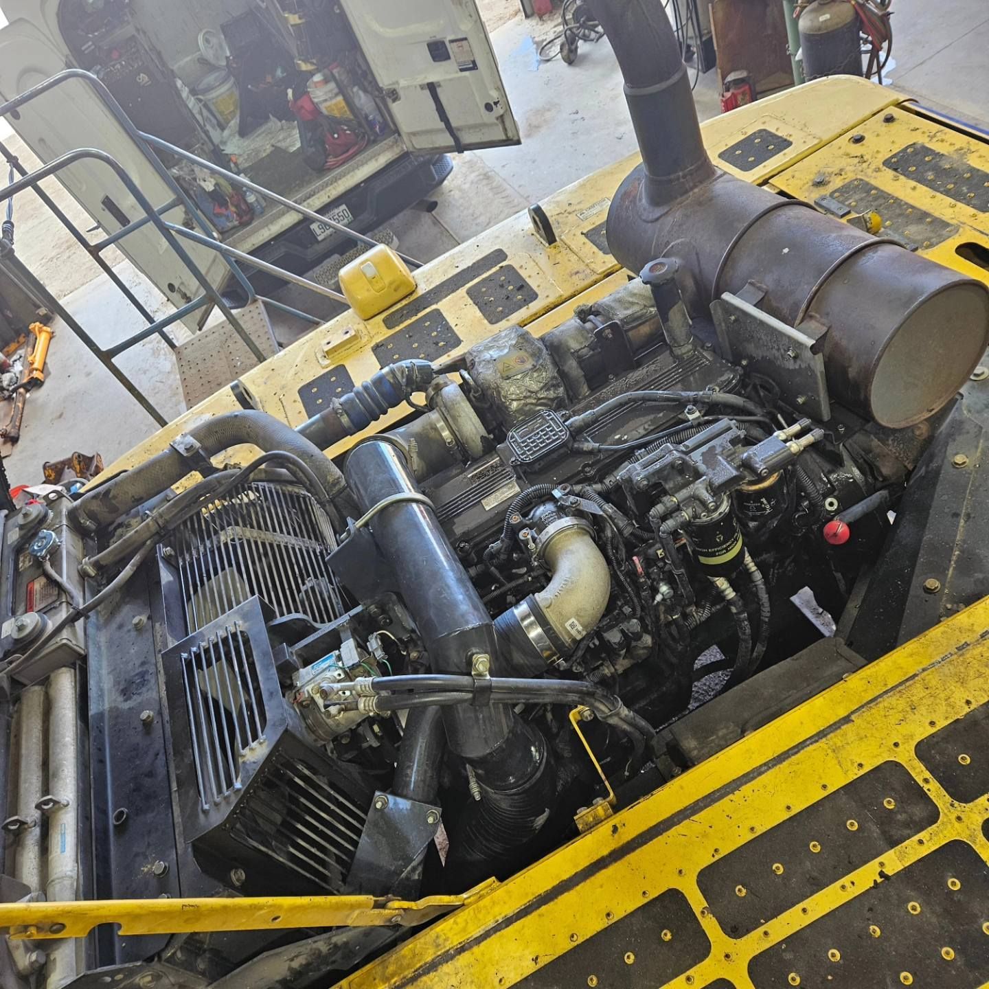 Moteur d'excavatrice jaune avec composants noirs, probablement à l'extérieur dans un environnement de travail.