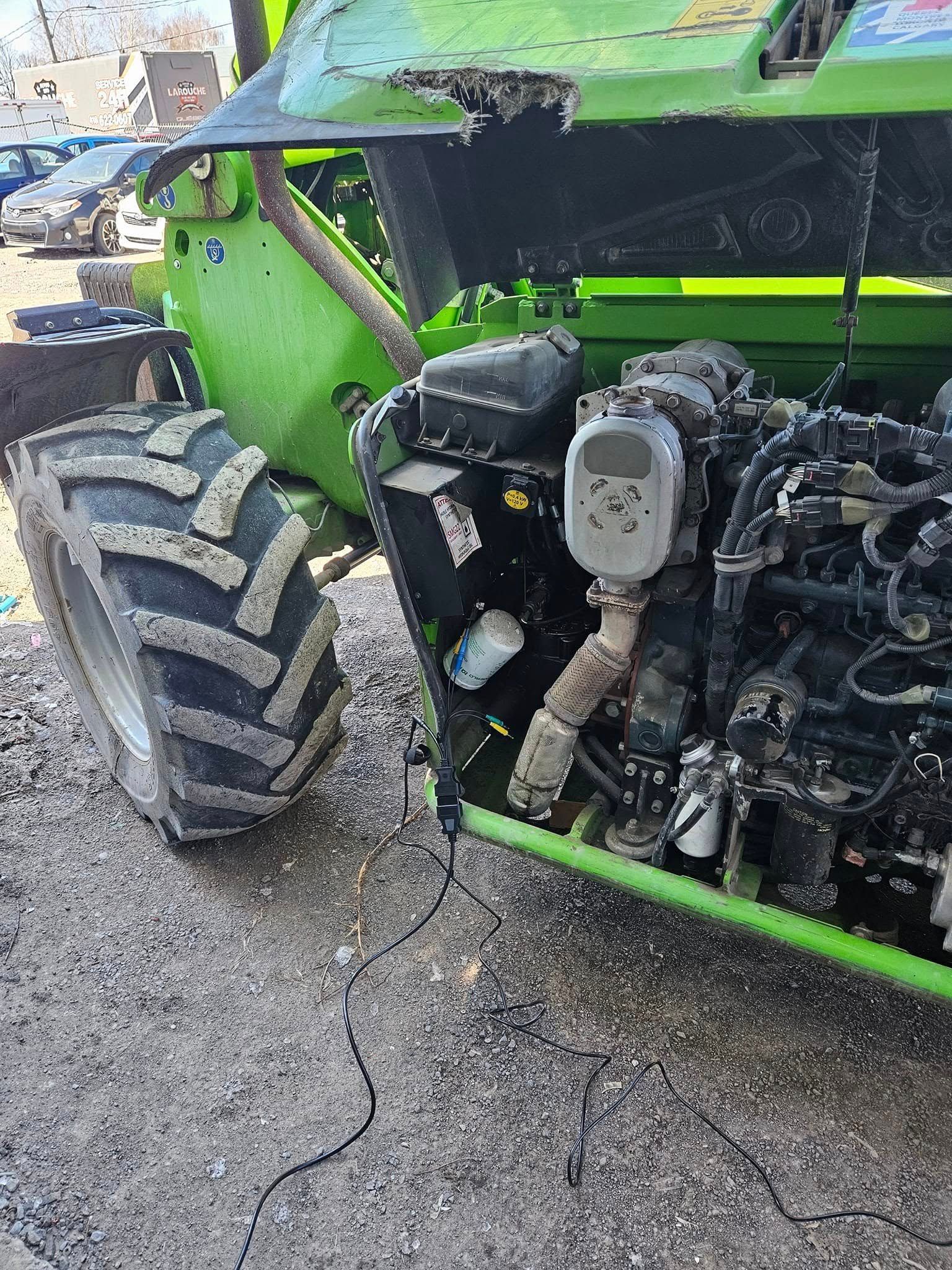 Véhicule de construction vert avec un gros pneu, un moteur exposé et un affichage numérique.