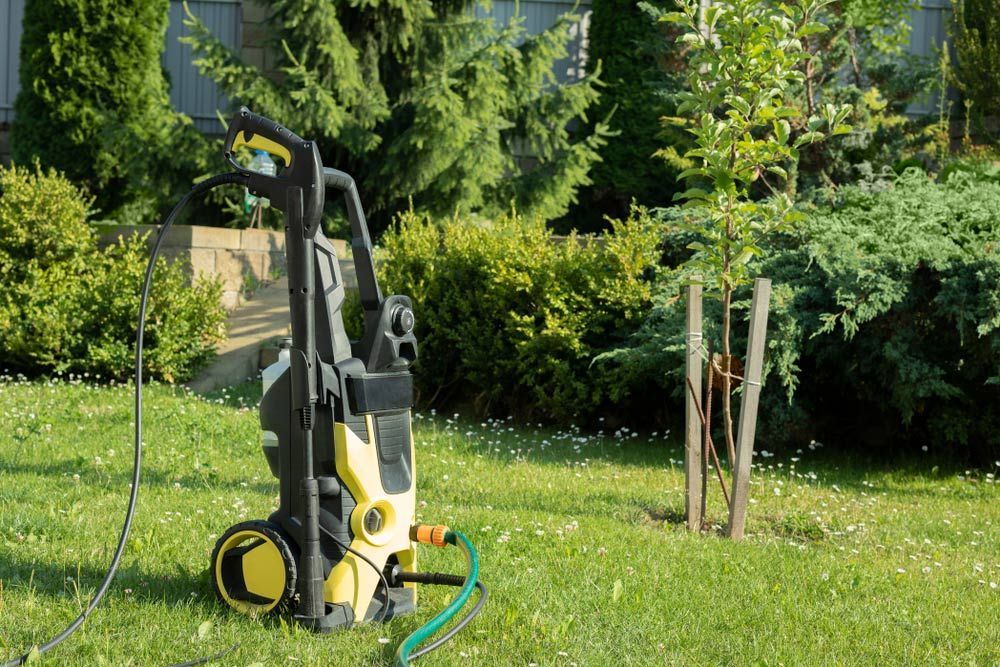 Pressure Washer on a Grassy Lawn Next to a Small Tree — Gloucester Outdoor Solutions In Stroud, NSW